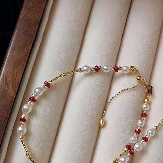 Pearl and ruby-red bead gold-tone bracelet on a velvet tray