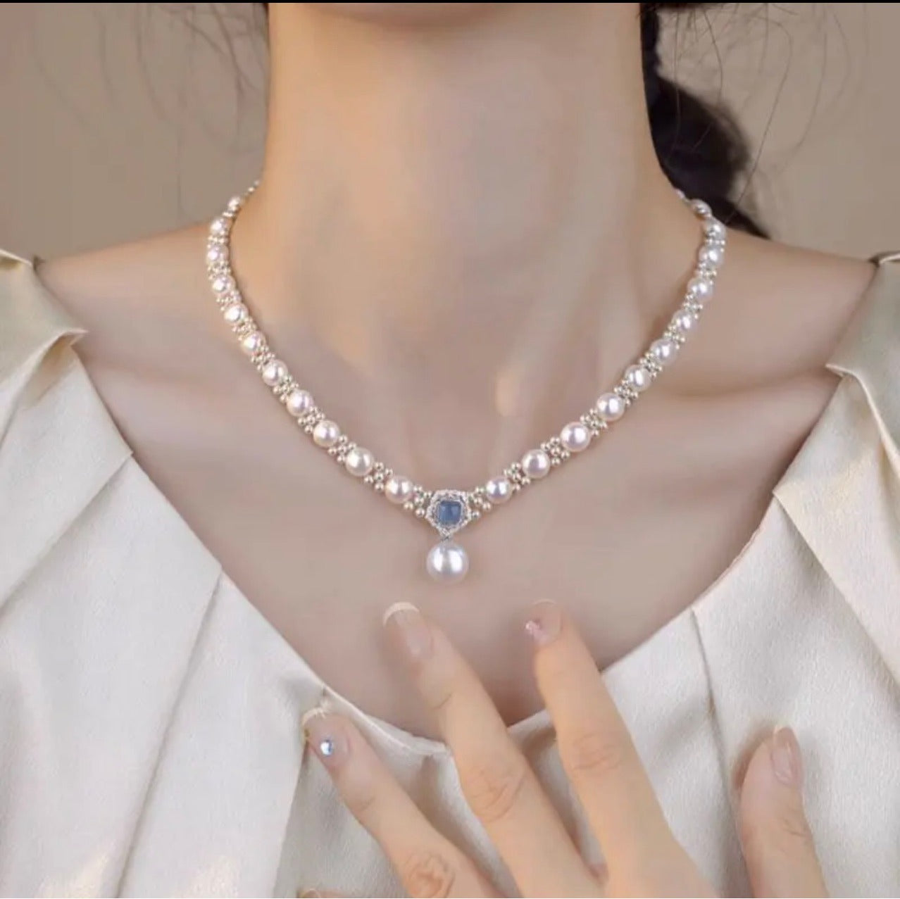 Blue stone halo pearl drop necklace worn at the collarbone