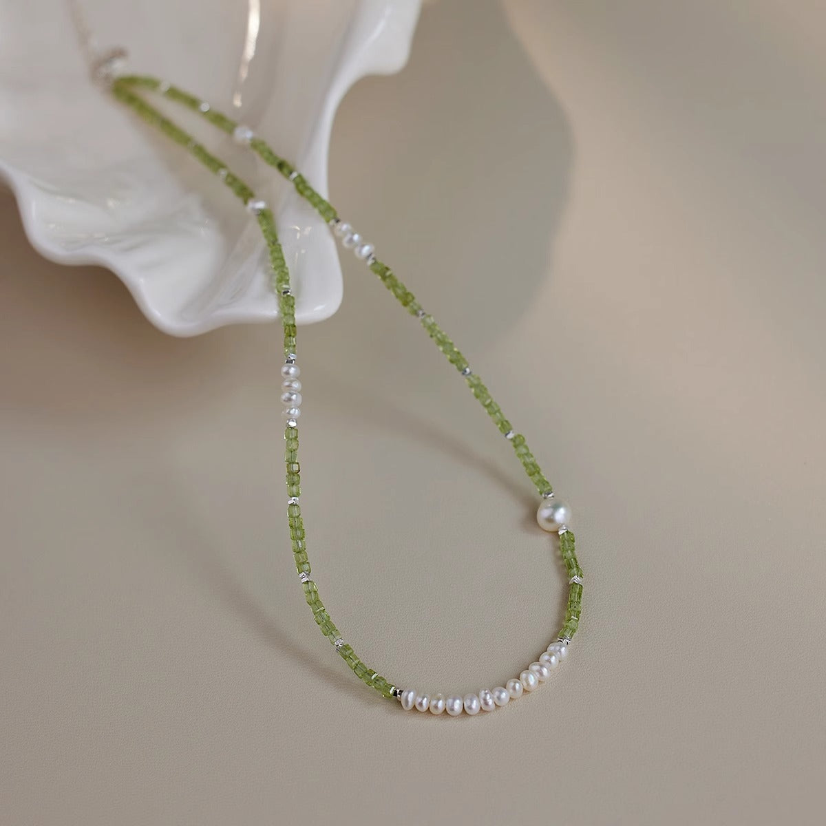 Peridot bead freshwater pearl necklace on a ceramic dish