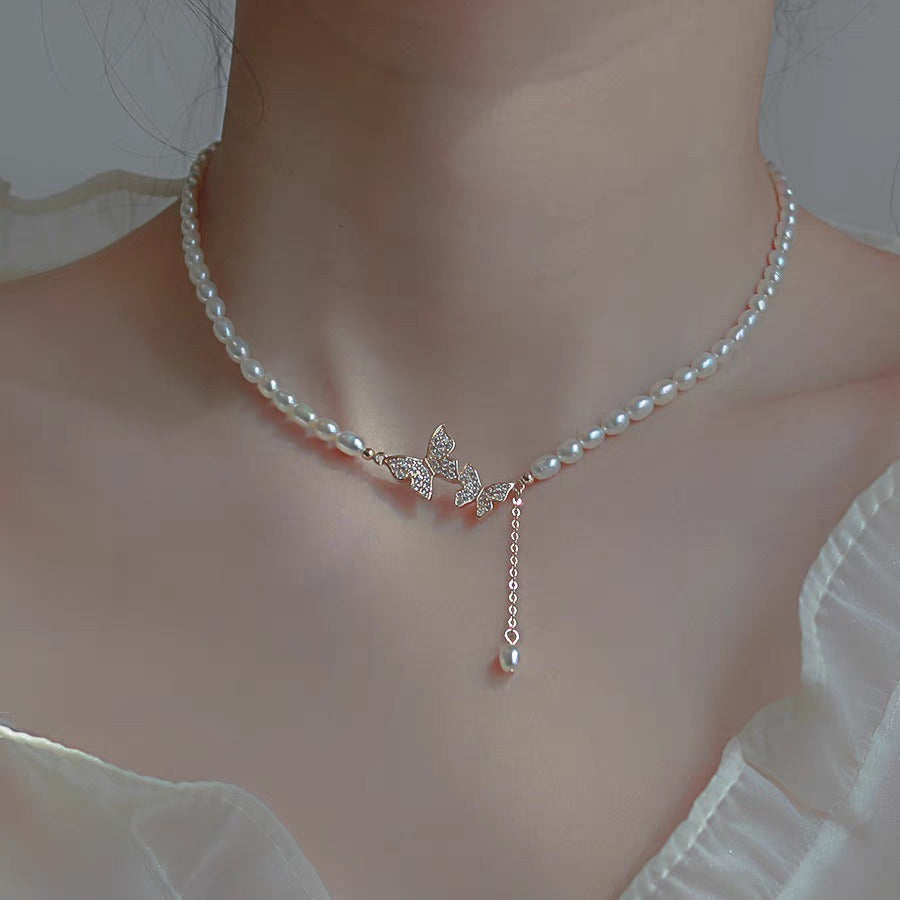 Close view of the butterfly charm and pearl drop on the neck