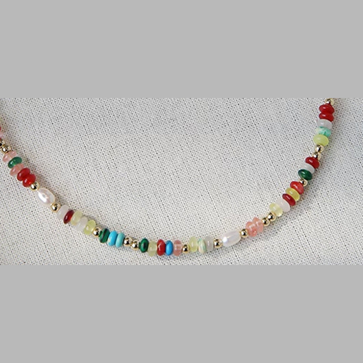 Close detail of colorful heishi discs, rice pearls and gold spacer beads