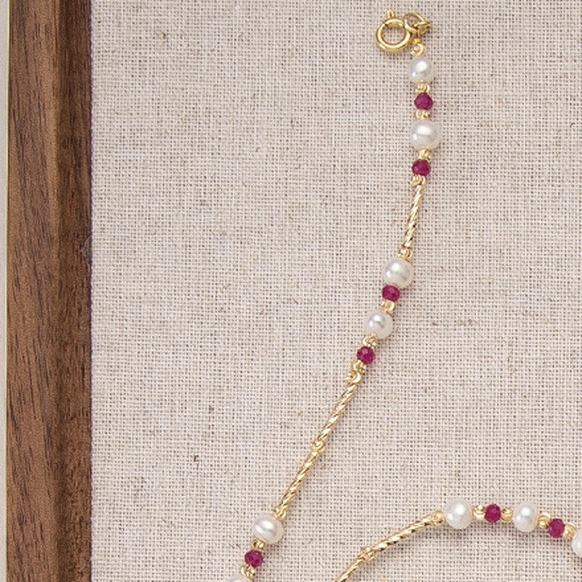 Close detail of freshwater pearls and faceted ruby-red beads on a gold-tone chain