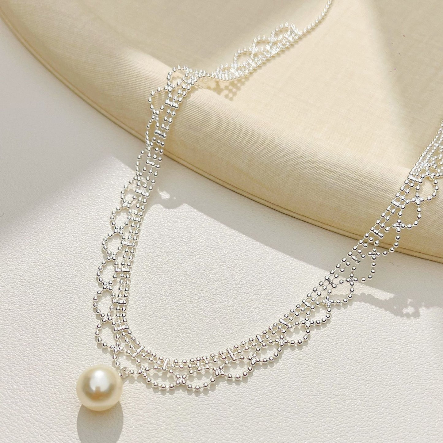 Silver lace pearl drop necklace draped on a tray
