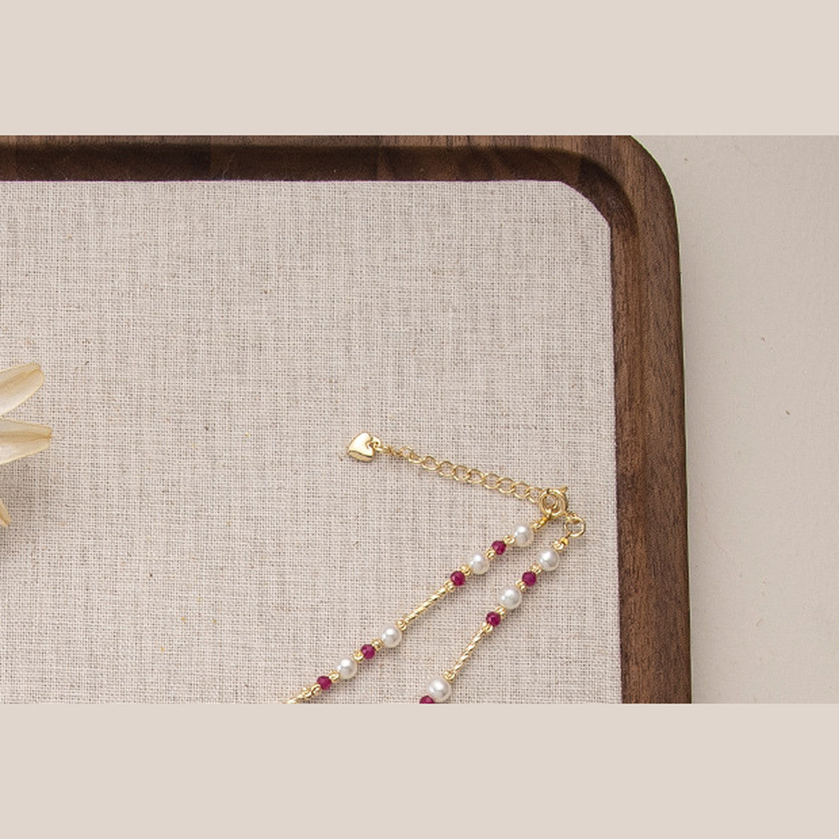 Gold-tone lobster clasp and small heart charm on the pearl and ruby bead necklace